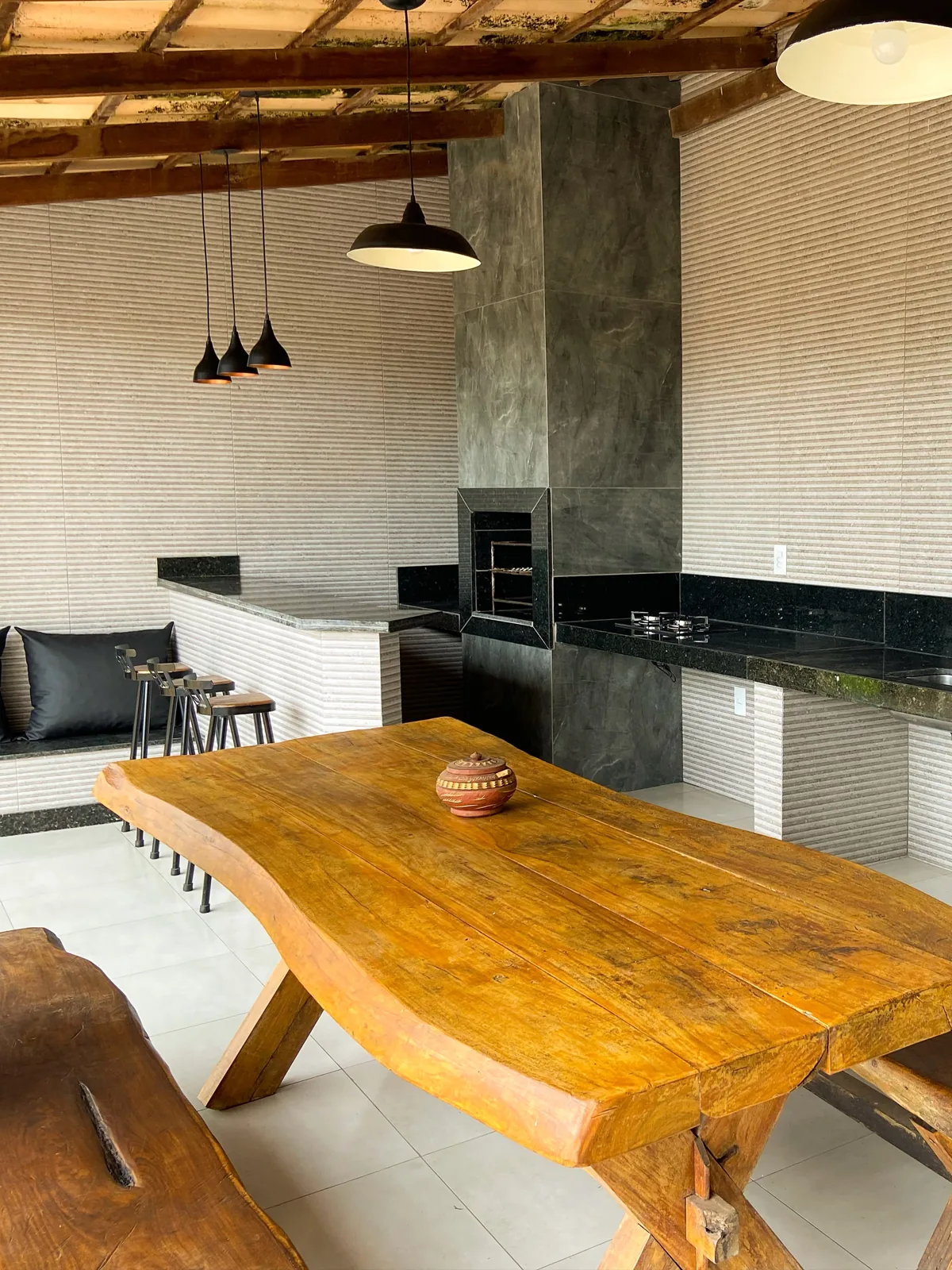 Mesa e bancos de madeira na área gourmet
