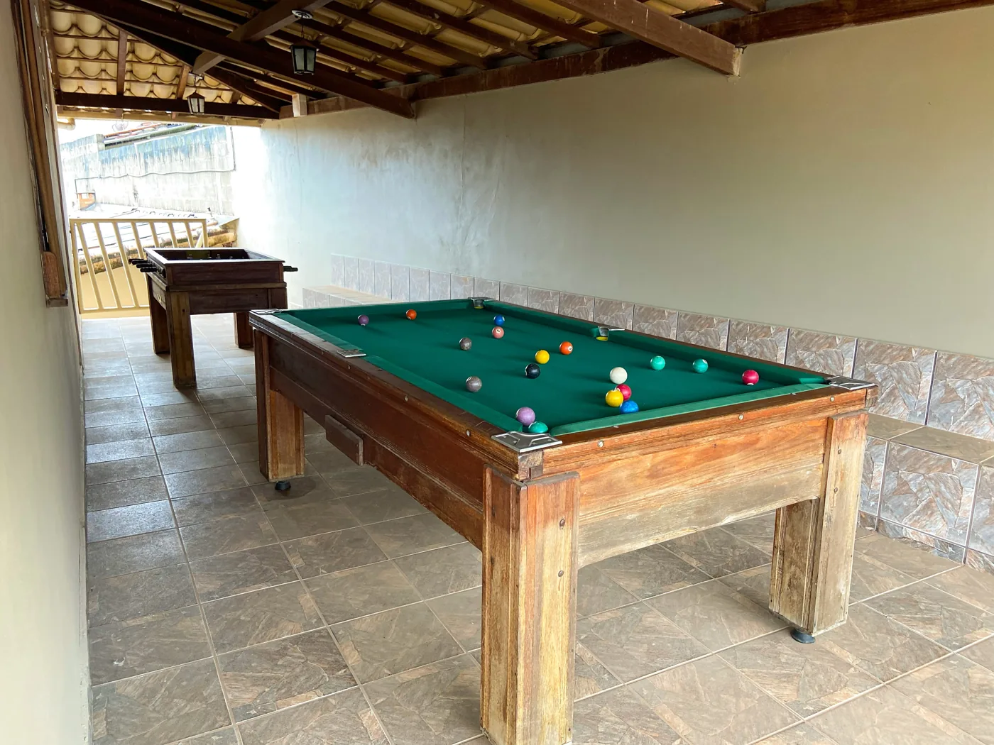 Espaço coberto com mesas de sinuca e totó